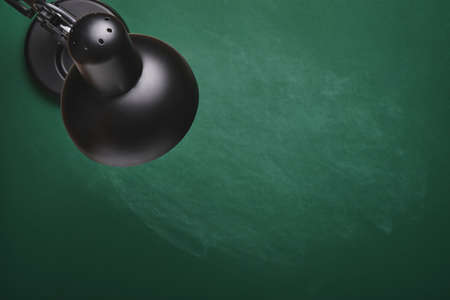 Black table lamp on green board. Concept back to school. Mock up for design. Copy space. Education Concept.の写真素材
