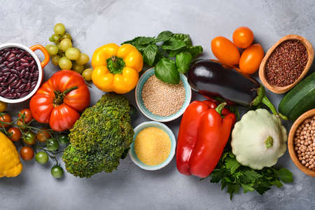 Assortment of fresh fruits and organic multicolored rainbow vegetables on gray concrete background....