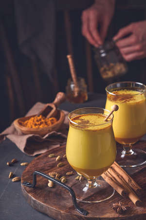 Turmeric golden milk latte with cinnamon sticks and honey. Healthy ayurvedic drink. Trendy Asian natural detox beverage with spices for vegans. Copy space.の写真素材