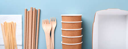 Paper cups, dishes, bag, wooden forks, drinking straws, fast food containers, wooden cutlery on light blue background. Eco craft paper tableware. Recycling and food delivery concept. Mock up. Top viewの写真素材