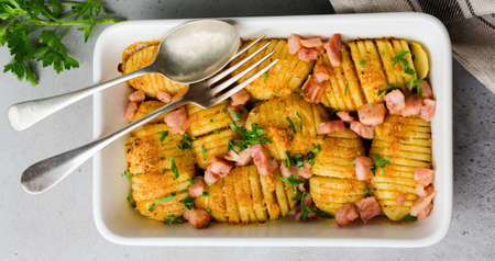 Baked potatoes with ham, herbs and breadcrumbs on gray light background. Scandinavian cuisine. Top view.の写真素材