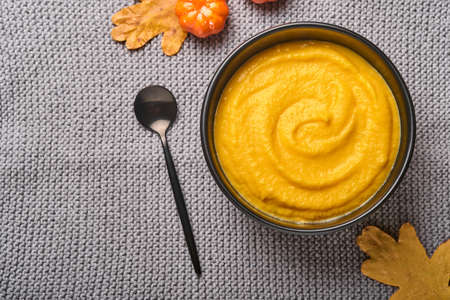 Pumpkin traditional soup with creamy silky texture with sage leaves and red pepper in black plate or bowl. Old gray background. Copy space. Mock up. Top view, flat lay.の写真素材