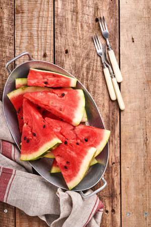 Slices of fresh watermelon in plate on wooden background. Mock up for design. Copy space.の写真素材