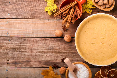 Pumpkin and food ingredients, spices, cinnamon and kitchen utencil on old rustic wooden background. Concept homemade baking for holiday. Cooking pumpkin pie and cookies for Thanksgiving day.の写真素材
