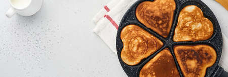 Pancakes in shape of breakfast hearts with chocolate sauce in gray ceramic plate, cup of coffee on gray concrete background. Table setting for Valentines Day breakfast. Top view copy space. Banner.の写真素材