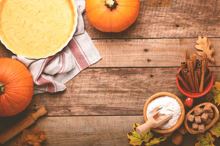 Pumpkin and food ingredients, spices, cinnamon and kitchen utencil on old rustic wooden background. Concept homemade baking for holiday. Cooking pumpkin pie and cookies for Thanksgiving day.の写真素材