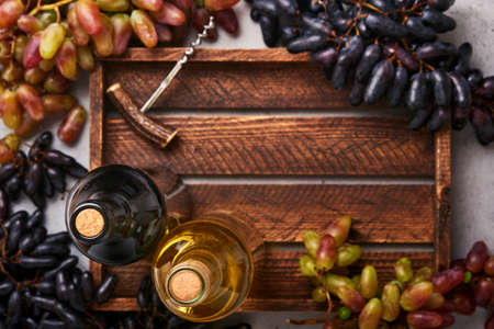 Two Wine bottles with grapes and wineglasses on old gray concrete table background with copy space. Red wine with a vine branch. Wine composition on rustic background. Mock up.の写真素材