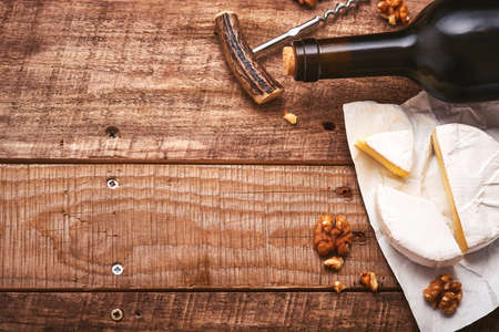 Bottle wine with corkscrew. with grapes, slice cheese camembert, nut on old gray concrete table background with copy space. Red wine with a vine branch. Wine composition on rustic background. Mock up.の写真素材