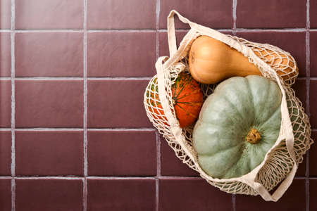 Pumpkin. Autumn food background with cinnamon, nuts and seasonal spices on old ceramic tiles background. Cooking pumpkin or apple pie and cookies for Thanksgiving and autumn holidays. Top view.の写真素材