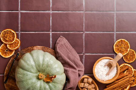 Pumpkin. Autumn food background with cinnamon, nuts and seasonal spices on old ceramic tiles background. Cooking pumpkin or apple pie and cookies for Thanksgiving and autumn holidays. Top view.の写真素材