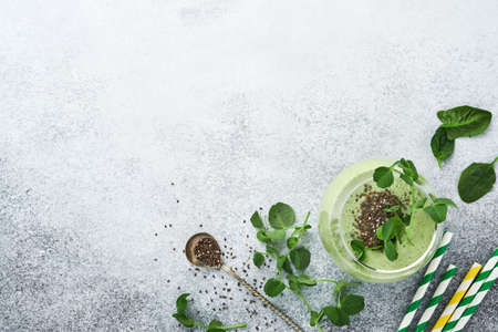 Ingredients for green smoothie, fresh organic spinach pea microgreens, banana, kiwi, apple and chia seed over light grey concrete background. Healthy eating ingredients. Top view, copy spaceの写真素材