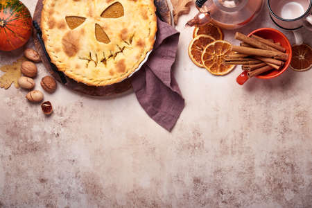 Halloween food. Homemade pumpkin pie or tart with a scary face for Halloween on a wooden table. Copy space. Halloween food concept.の写真素材