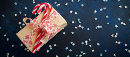 Christmas candy, gift box and confectioner's multicolored powder on dark blue stone or concrete...