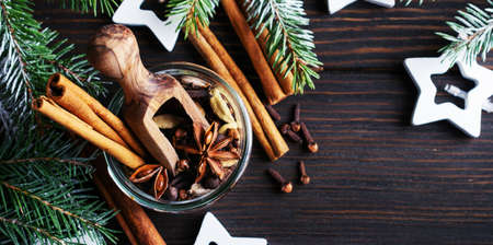 Mix of mulled wine seasonings in a jar of anise, cardamom, allspice, cinnamon sticks, cloves on a wooden dark background. Place for text.の写真素材