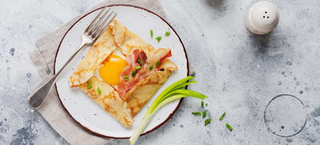 Crepe with fried egg, cheese, bacon and green onions for breakfast on a light gray concrete background.の写真素材