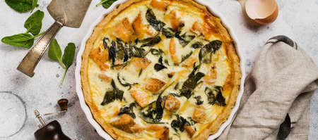 Homemade quiche tart with red fish and spinach on light wooden background. Vintage style. Top view.の写真素材
