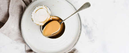 Condensed or evaporated milk in open tin on light concrete table. Top view.の写真素材