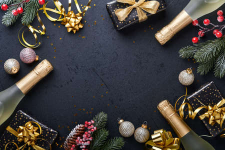 Holiday gift box or present with ribbon, golden confetti and gold baubles on black background. Magic christmas greeting card. Christmas Decoration. Border design. Mock up. Top view.の写真素材