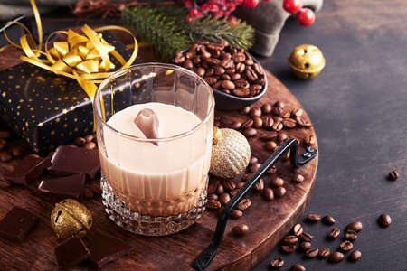 Glass of Irish cream barley liqueur with ice, roasted coffee beans, cinnamon, Christmas decoration...