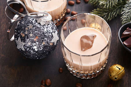 Glass of Irish cream barley liqueur with ice, roasted coffee beans, cinnamon, Christmas decoration...