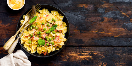 Fettuccine pasta with bacon and green peas and parmesan cheese in old pan on old dark wooden background. Top view.の写真素材