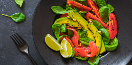 Avocado, salmon, spinach, tomato, pine nuts and black sesame salad in a black ceramic plate. Top view.の写真素材
