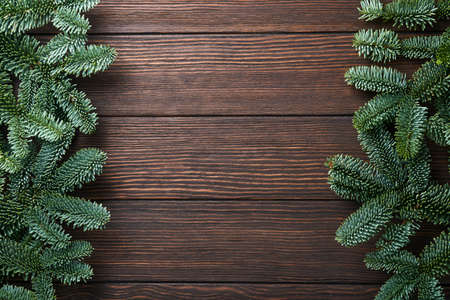 Christmas fir tree branches, Christmas balls, gift box, wooden snowflakes and stars on old brawn wooden background for your xmas greetings. Top view with copy space. Christmas greeting card.の写真素材