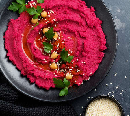 Homemade beetroot hummus in black ceramic dish on old dark concrete background. Selective focus. Top view.の写真素材