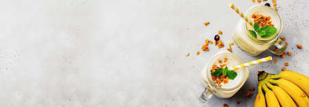 Banana smoothie with granola, dried fruits and mint on gray concrete background. Top view.の写真素材