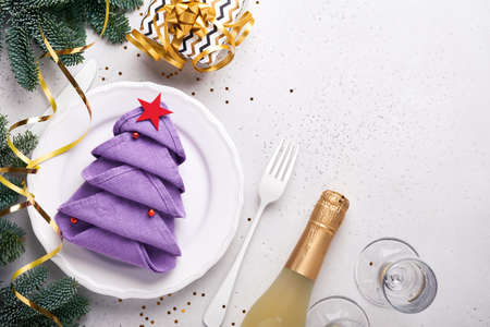 Christmas table setting white color with silverware, napkin folded as Christmas tree trendy color very peri in 2022 Year, Christmas balls, champagne, glasses on white background. Mock up.の写真素材