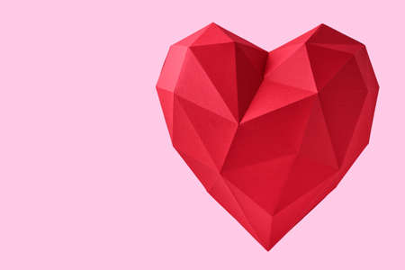 Red paper hearth isolated on pink background. Red polygonal paper heart for Valentine's day or any other Love invitation cards. Top view, copy space.の写真素材