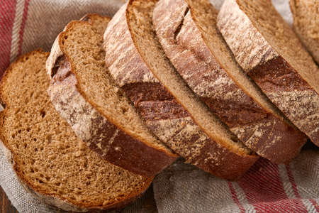Fresh homemade rye bread. Traditional spelled sourdough bread cut into slices on a rustic wooden...