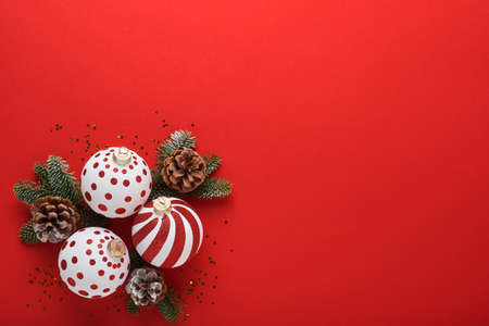 Christmas or New Year concept with white and red baubles ball, gift box and champagne with decorated ribbon and fir tree branches on red background. Happy New Year 2022. Mock up.の写真素材