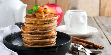 Stack of pancakes from buckwheat flour with baked apples and cinnamon on old wooden background. A healthy breakfast. Selective focus.の写真素材
