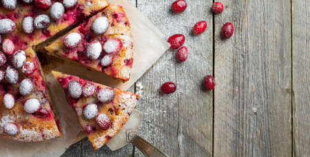 Homemade cranberry pie with walnuts, berries and powdered sugar. Top view. Space for text. Rustic style. Selective focus.の写真素材