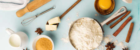 Baking background with ingredients flour, eggs, sugar, butter, cinnamon, anise star and kitchen tools on blue rustic table. Selective focus. Top view.の写真素材