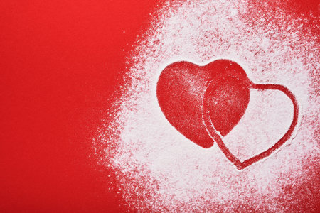 Heart shape frame made of flour on red background. Happy Valentines day, mothers day. Valentines day gift bakery concept for card or creative design. Top view.の写真素材