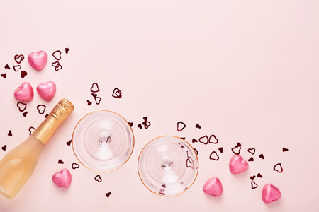 Valentines day greeting card with champagne bottle, tow glasses, chocolate hearts and gift box on pink background. Top view with space for greetings. Greeting card with copy space.の写真素材
