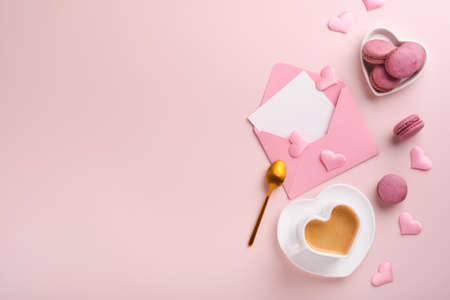 Valentines Day card. Pink empty envelope, macaron macaroon cookie and heart shaped coffee cup on pink background. 8 March, Womens Mothers Valentines Day, Birthday. Flat lay, top view, copy space.の写真素材
