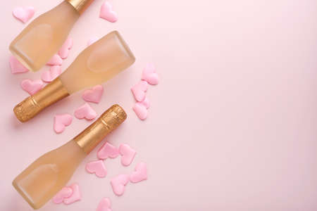 Valentines day greeting card with three champagne bottles and on pink background. Top view with...