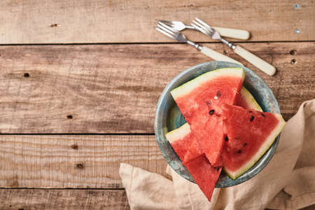 Slices of fresh watermelon in plate on wooden background. Mock up for design. Copy space.の写真素材