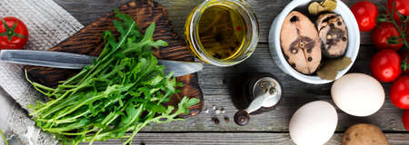 Set of raw ingredients potatoes, eggs, fresh arugula, olive oil, pepper, canned tuna, tomatoes cherry, salt to prepare a salad Nicoise on the old wooden background. Rustic style, top view.の写真素材