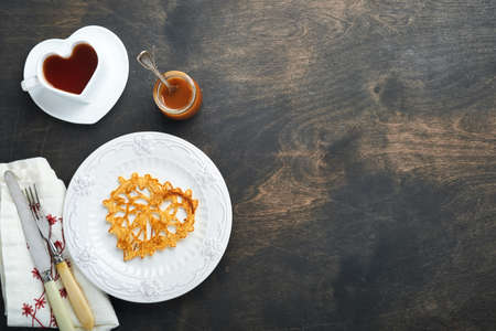 Heart shaped lace pancakes or crepes on white plate on old rustic background. Table setting for your...
