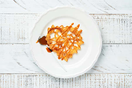Heart shaped lace pancakes or crepes sprinkled with caramel on white plate on old rustic background. Table setting for your favorite Valentines Day breakfast. Top view copy space.の写真素材