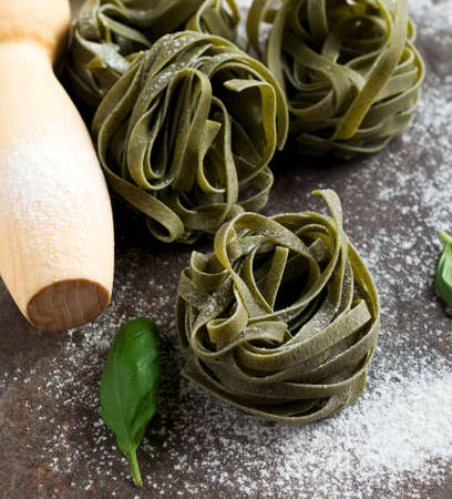 Tagliatelle Paglia e Fieno. on a dark background. Making homemade pasta linguine on rustic kitchen table with flour, rolling pin and pasta. selective focus.の写真素材