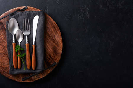 vintage silverware. Rustic vintage set of wooden spoon and fork on wooden platter on black...