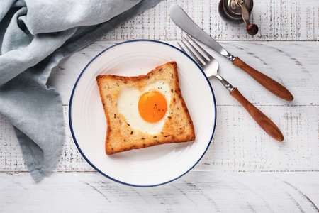 Heart shaped egg with toast and microgreens on light white wooden background, breakfast table top. Valentines day breakfast. top view. Mock up.の写真素材