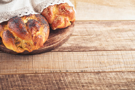 Shabbat Shalom. Bread challah with sesame seeds and poppy seeds on wooden background. Traditional...