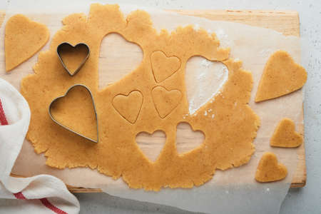 Baking ingredients and kitchen utensils on a white background top view. Preparing heart sugar...