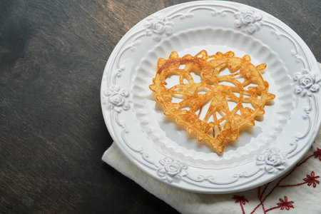 Heart shaped lace pancakes or crepes on white plate on old rustic background. Table setting for your...